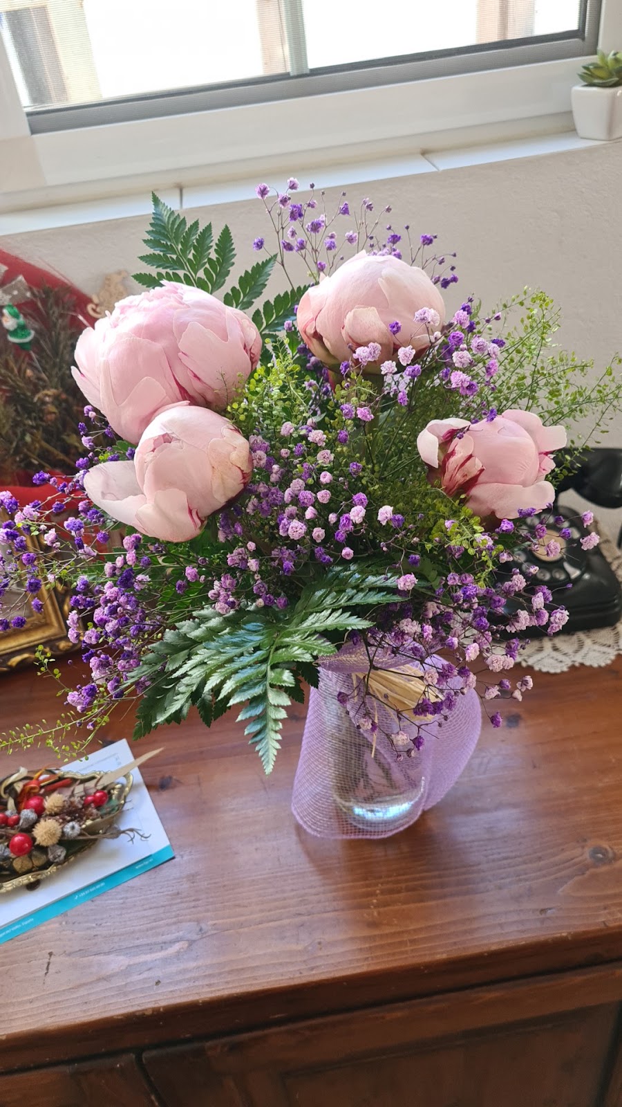 Ramo de peonías rosas en jarrón de cristal sobre una cómoda de madera