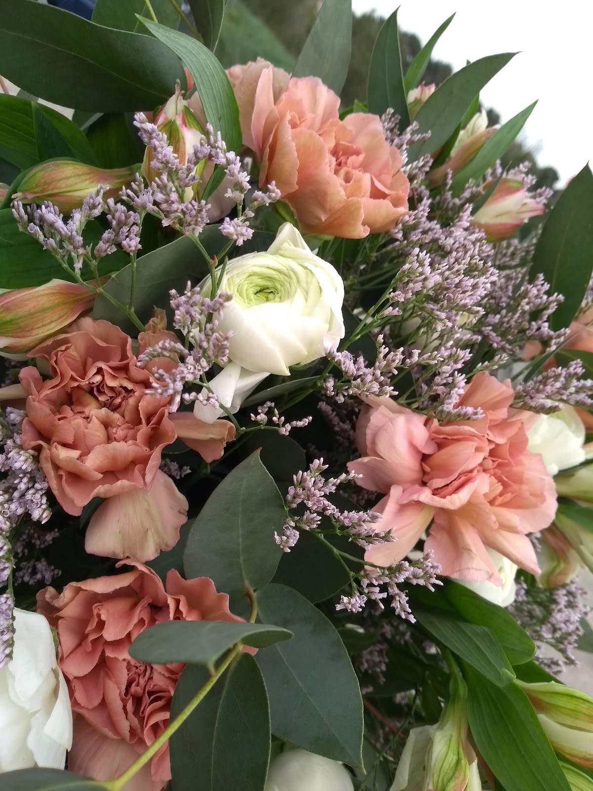 Ramo de ranúnculos y lisianthus en tonos coral con eucalipto