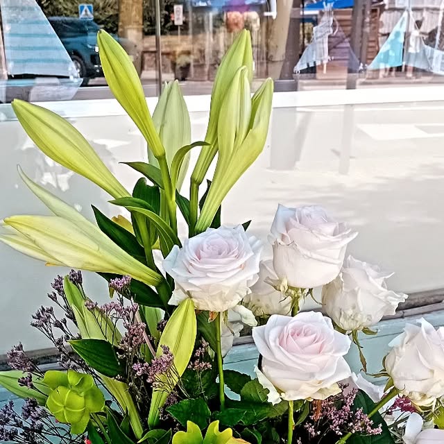 Lirios blancos y rosas rosadas en el escaparate de la tienda