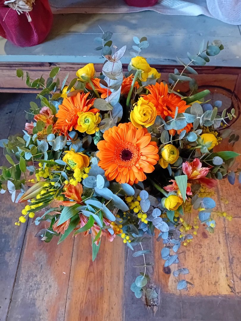 Composición de gerberas naranjas y ranúnculos con eucalipto